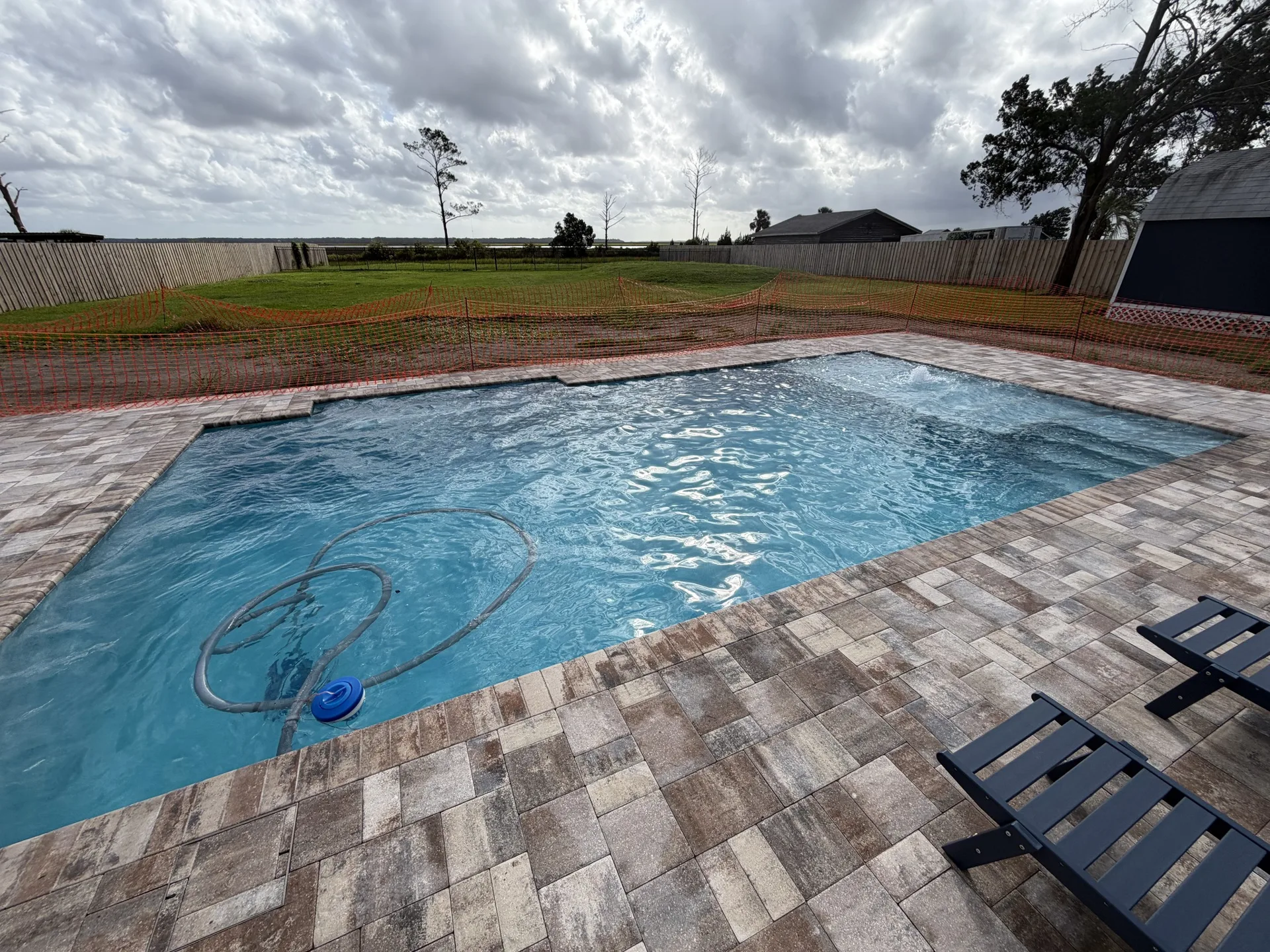 Finished custom pool with paver deck and chairs built by Scott's Pools & Spas in Jacksonville