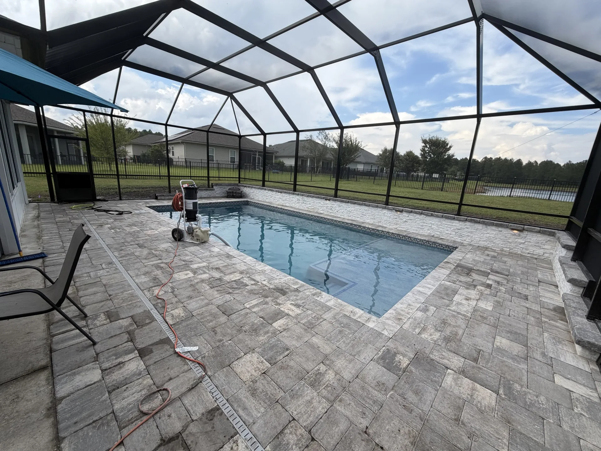 Screened-in custom pool with pavers and tanning ledge built by Scott's Pools & Spas in Jacksonville